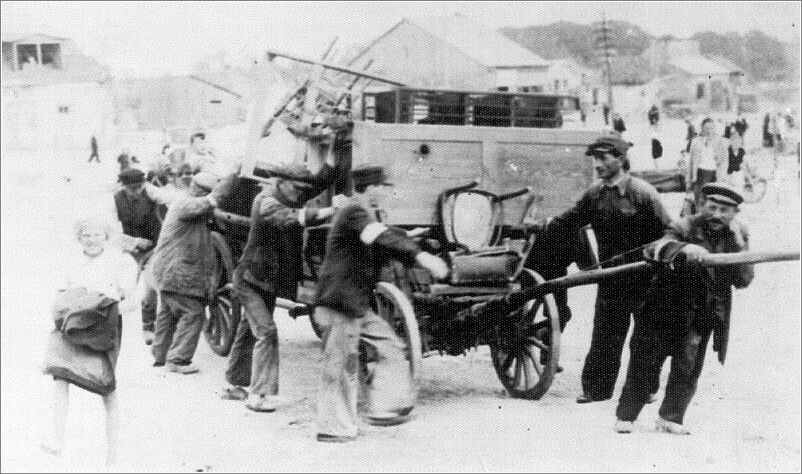Jews being relocated to the Radom ghetto, pushing and pulling a wagon loaded with furniture.